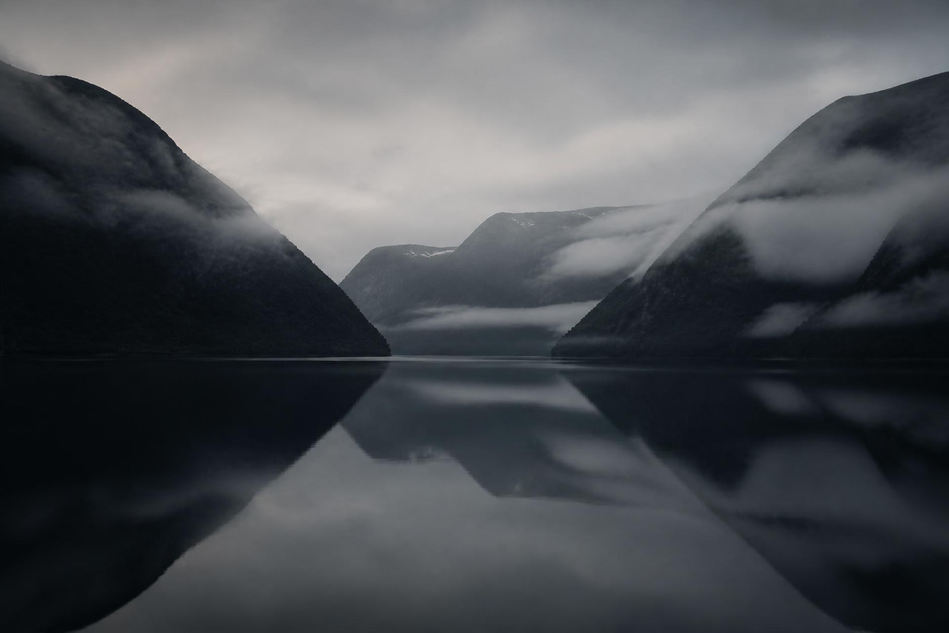 Stille nordisk fjord i tåke ved daggry
